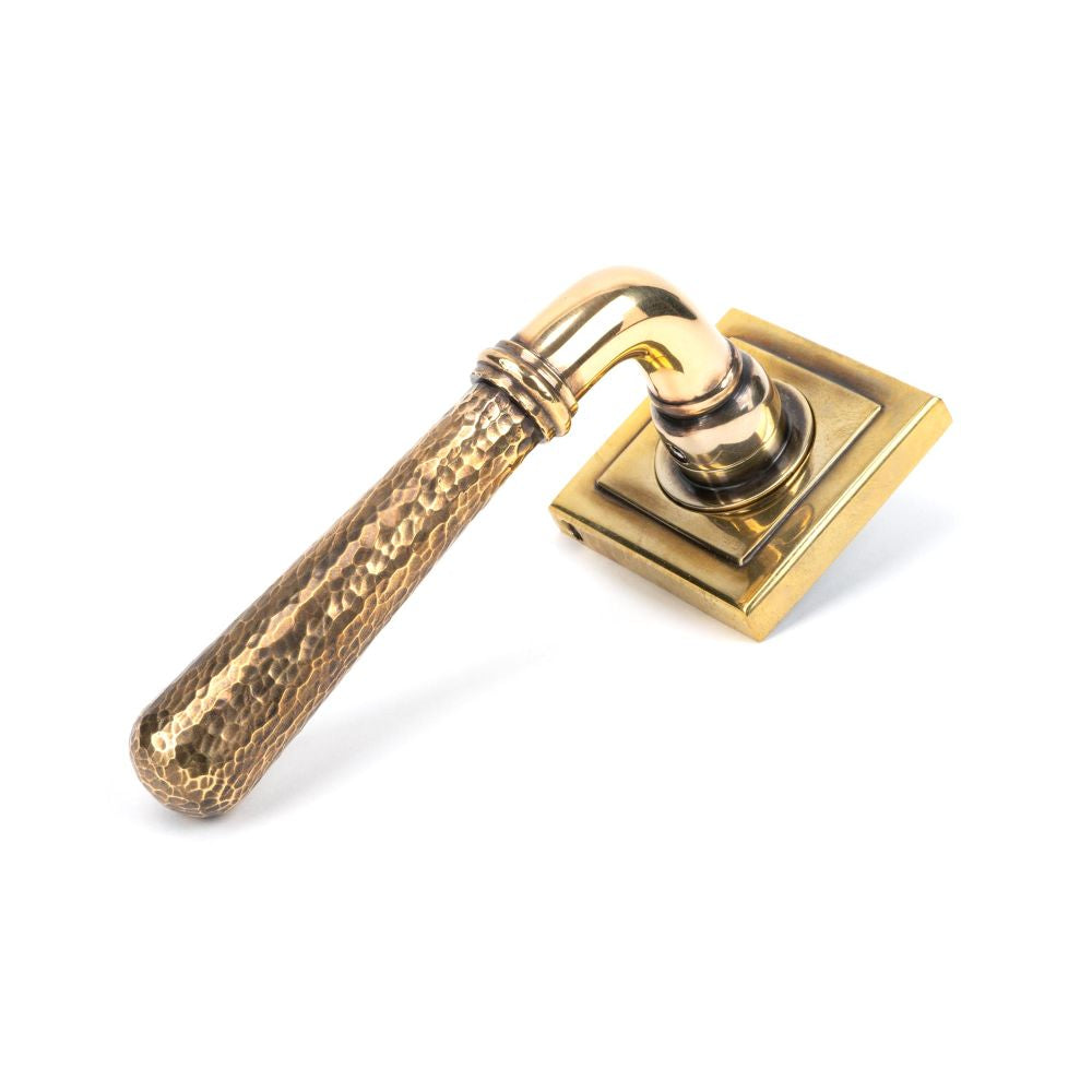 This is an image showing From The Anvil - Aged Brass Hammered Newbury Lever on Rose Set (Square) - Unspru available from trade door handles, quick delivery and discounted prices