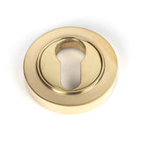 This is an image showing From The Anvil - Polished Brass Round Euro Escutcheon (Plain) available from trade door handles, quick delivery and discounted prices