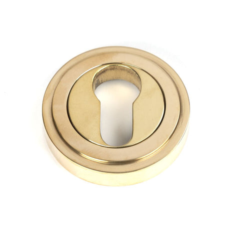 This is an image showing From The Anvil - Polished Brass Round Euro Escutcheon (Art Deco) available from trade door handles, quick delivery and discounted prices