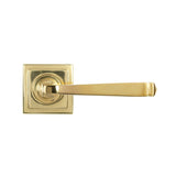 This is an image showing From The Anvil - Polished Brass Avon Round Lever on Rose Set (Square) available from trade door handles, quick delivery and discounted prices