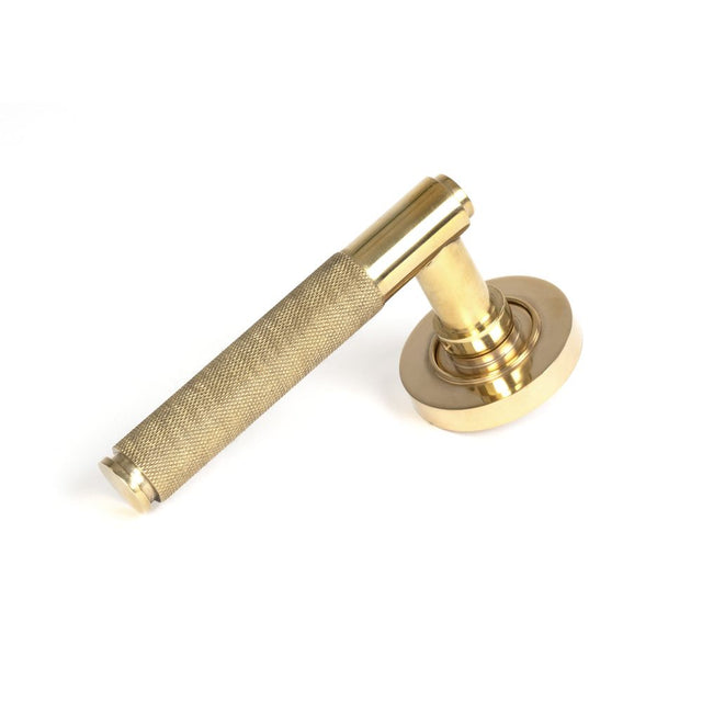 This is an image showing From The Anvil - Polished Brass Brompton Lever on Rose Set (Plain) available from trade door handles, quick delivery and discounted prices