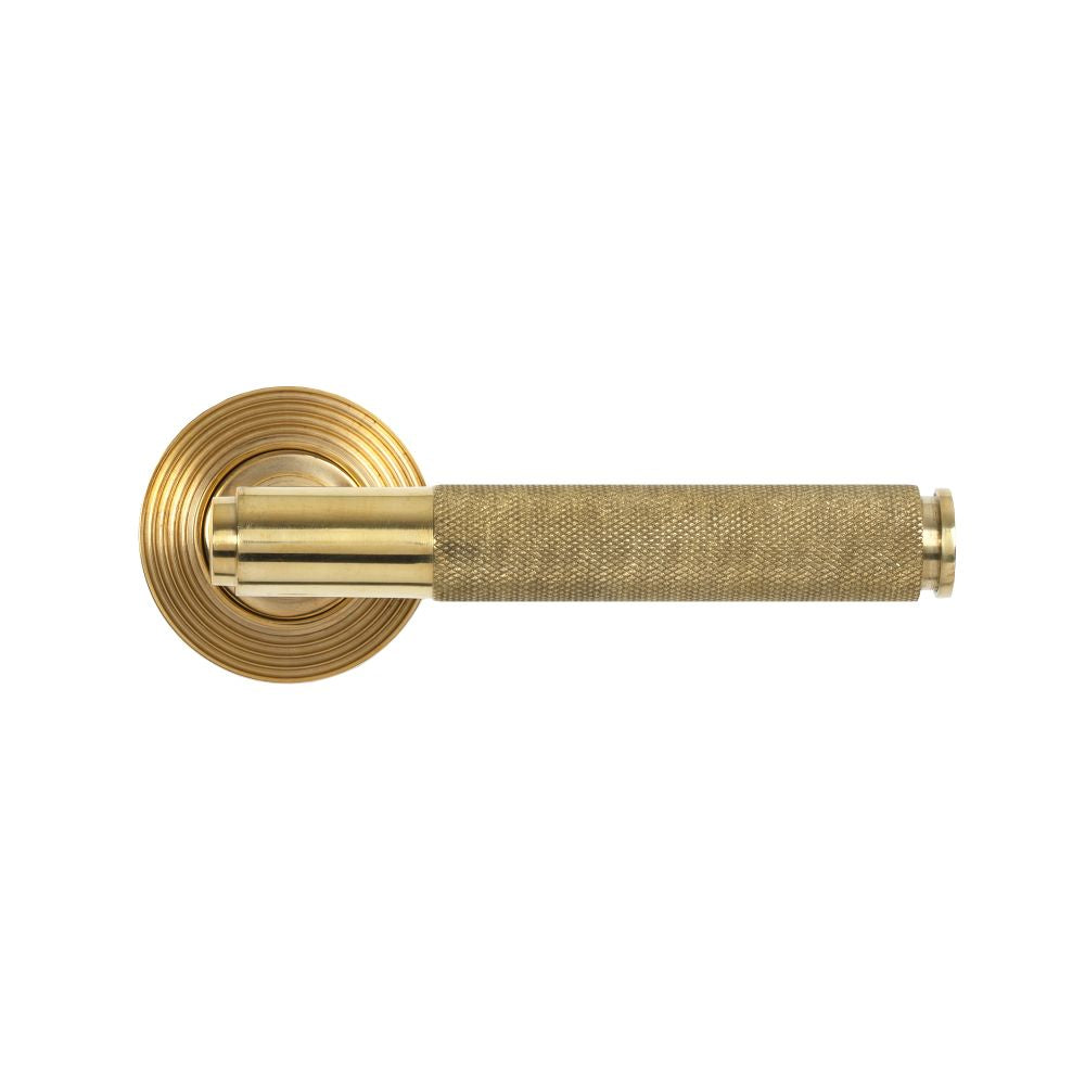 This is an image showing From The Anvil - Polished Brass Brompton Lever on Rose Set (Beehive) available from trade door handles, quick delivery and discounted prices