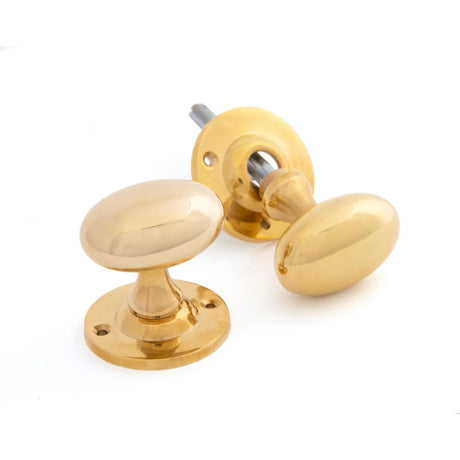 This is an image showing From The Anvil - Polished Brass Oval Mortice/Rim Knob Set available from trade door handles, quick delivery and discounted prices