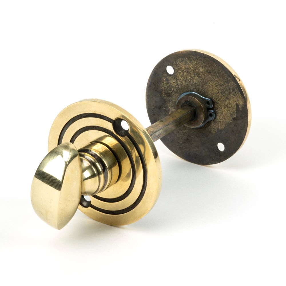 This is an image showing From The Anvil - Aged Brass Round Bathroom Thumbturn available from trade door handles, quick delivery and discounted prices