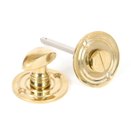 This is an image showing From The Anvil - Polished Brass Round Bathroom Thumbturn available from trade door handles, quick delivery and discounted prices