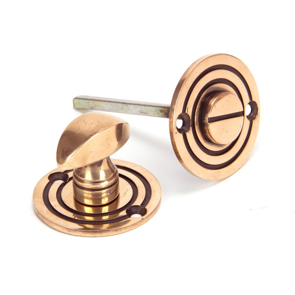 This is an image showing From The Anvil - Polished Bronze Round Bathroom Thumbturn available from trade door handles, quick delivery and discounted prices