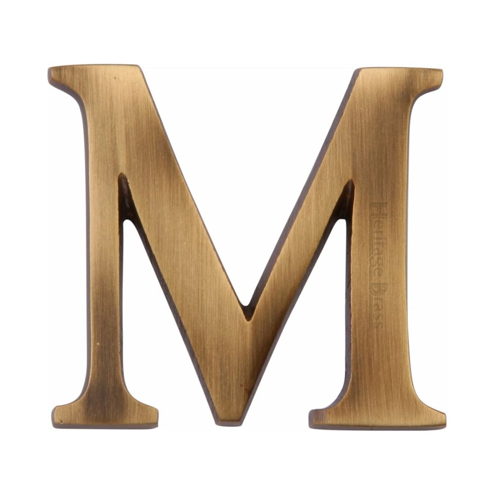 This is an image of a Heritage Brass - Alphabet M Pin Fix 51mm (2") Antique Brass Finish, c1565-2-m-at that is available to order from Trade Door Handles in Kendal.