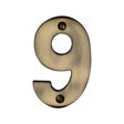 This is an image of a Heritage Brass - Numeral 9 Face Fix 76mm (3") Antique Brass Finish, c1566-9-at that is available to order from Trade Door Handles in Kendal.