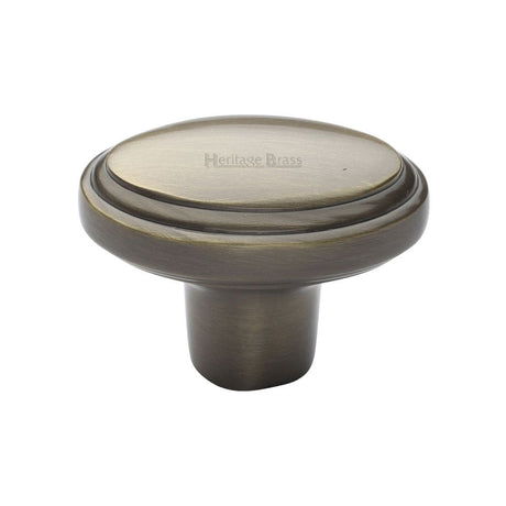 This is an image of a Heritage Brass - Cabinet Knob Stepped Oval Design 41mm Antique Brass Finish, c3975-at that is available to order from Trade Door Handles in Kendal.