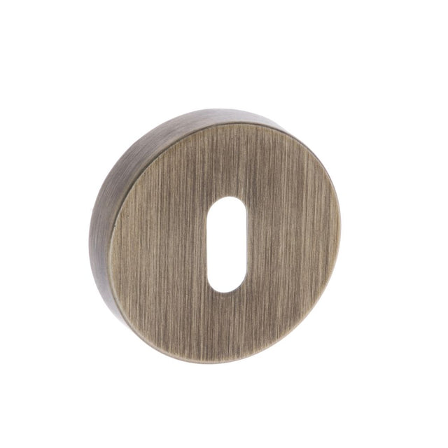 This is an image of Forme Key Escutcheon on Minimal Round Rose - Yester Bronze available to order from Trade Door Handles.