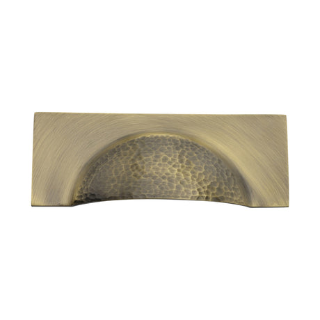 This is an image of a Heritage Brass - Drawer Cup Pull Hampshire Hammered Design 57mm CTC Antique Brass Finish, ham2764-at that is available to order from Trade Door Handles in Kendal.