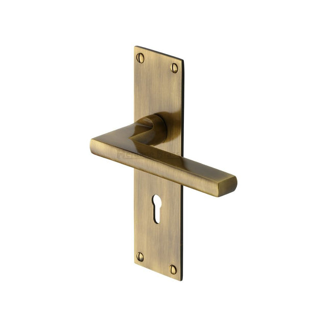 This is an image of a Heritage Brass - Door Handle Lever Lock Trident Design Antique Brass Finish, tri1300-at that is available to order from Trade Door Handles in Kendal.