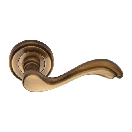 This is an image of a Heritage Brass - Door Handle Lever Latch on Round Rose Lisboa Design Antique Brass, v1601-at that is available to order from Trade Door Handles in Kendal.