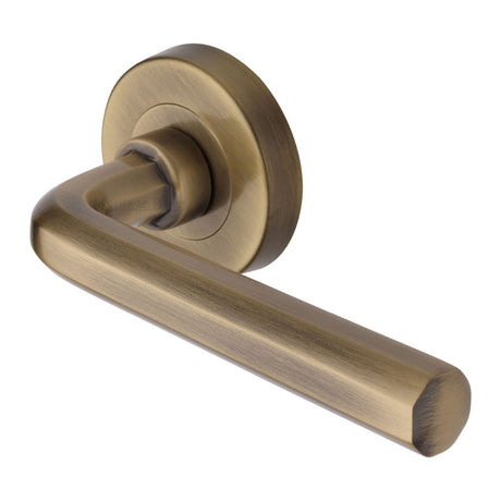 This is an image of a Heritage Brass - Door Handle Lever Latch on Round Rose Octave Design Antique Brass, v4545-at that is available to order from Trade Door Handles in Kendal.