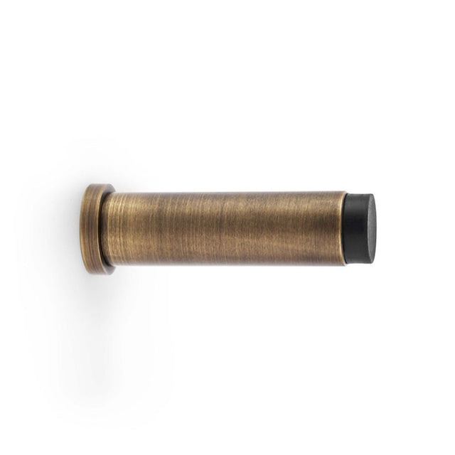 This is an image showing Alexander & Wilks Plain Projection Cylinder Door Stop - Antique Brass aw601-75-ab available to order from Trade Door Handles in Kendal, quick delivery and discounted prices.