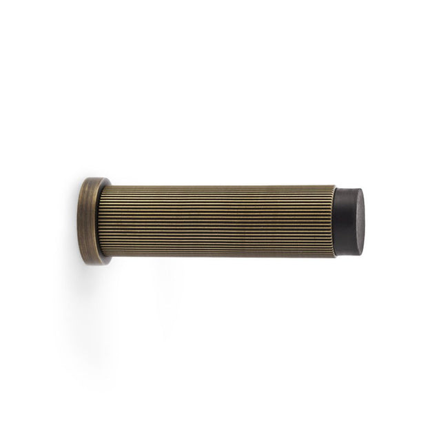 This is an image showing Alexander & Wilks Reeded Projection Door Stop - Antique Brass aw602-75-ab available to order from Trade Door Handles in Kendal, quick delivery and discounted prices.