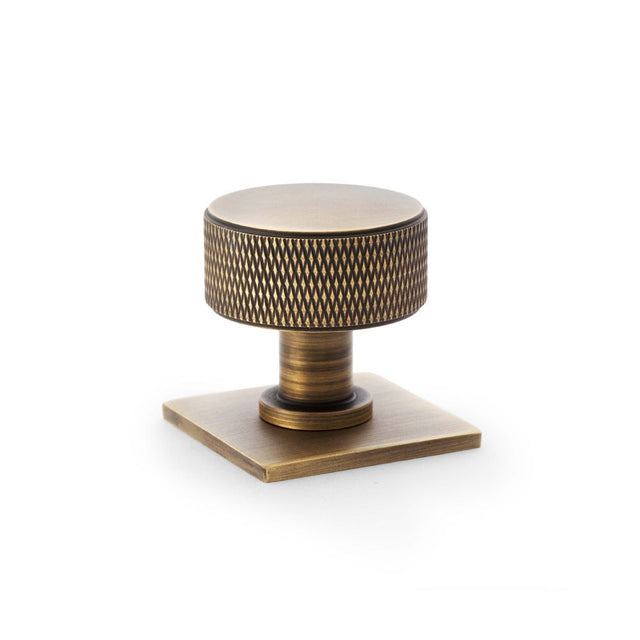 This is an image showing Alexander & Wilks Lucia Knurled Cupboard Knob - Antique Brass - 35mm aw807k-35-ab available to order from Trade Door Handles in Kendal, quick delivery and discounted prices.