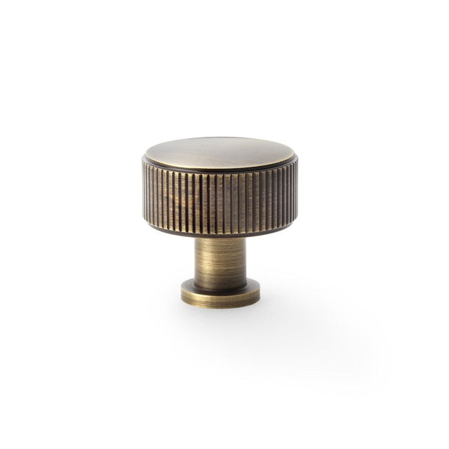 This is an image showing Alexander & Wilks Lucia Reeded Cupboard Knob - Antique Brass - 35mm aw807r-35-ab available to order from Trade Door Handles in Kendal, quick delivery and discounted prices.