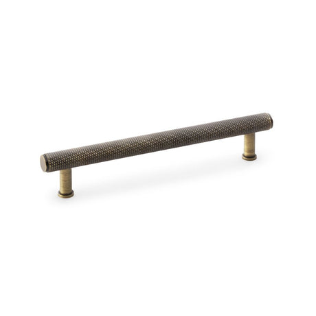 This is an image showing Alexander & Wilks Crispin Knurled T-bar Cupboard Pull Handle - Antique Brass - Centres 160mm aw809-160-ab available to order from Trade Door Handles in Kendal, quick delivery and discounted prices.