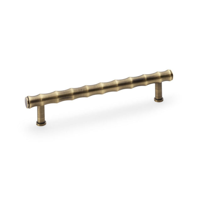 This is an image showing Alexander & Wilks Crispin Bamboo T-bar Cupboard Pull Handle - Antique Brass aw809b-160-ab available to order from Trade Door Handles in Kendal, quick delivery and discounted prices.