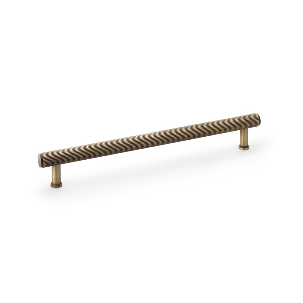 This is an image showing Alexander & Wilks Crispin Reeded T-bar Cupboard Pull Handle - Antique Brass - 224mm aw809r-224-ab available to order from Trade Door Handles in Kendal, quick delivery and discounted prices.