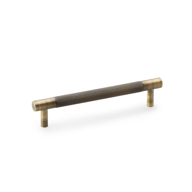 This is an image showing Alexander & Wilks Brunel Knurled T-Bar Cupboard Handle - Antique Brass - Centres 128mm aw810-128-ab available to order from Trade Door Handles in Kendal, quick delivery and discounted prices.