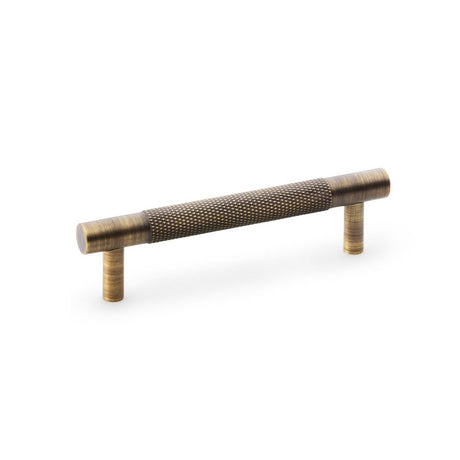 This is an image showing Alexander & Wilks Brunel Knurled T-Bar Cupboard Handle - Antique Brass - Centres 96mm aw810-96-ab available to order from Trade Door Handles in Kendal, quick delivery and discounted prices.