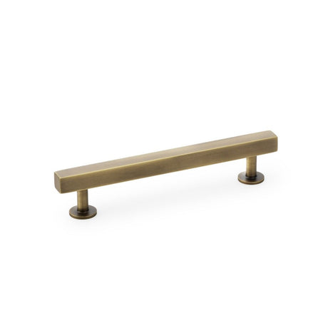 This is an image showing Alexander & Wilks Square T-Bar Cabinet Pull Handle - Antique Brass - Centres 128mm aw815-128-ab available to order from Trade Door Handles in Kendal, quick delivery and discounted prices.