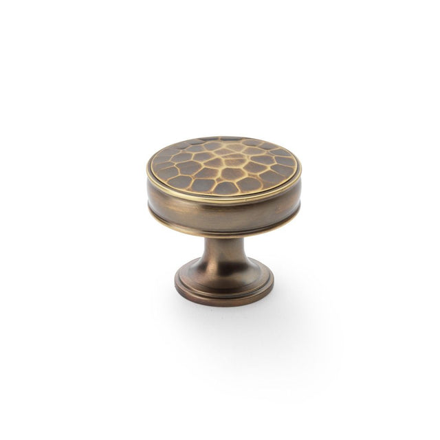 This is an image showing Alexander & Wilks Lynd Hammered Cupboard Knob - Antique Brass - 38mm aw818-38-ab available to order from Trade Door Handles in Kendal, quick delivery and discounted prices.