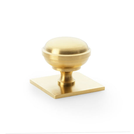 This is an image showing Alexander & Wilks Quantock Cupboard Knob on Square Backplate - Satin Brass PVD - 38mm aw826-38-sbpvd available to order from Trade Door Handles in Kendal, quick delivery and discounted prices.