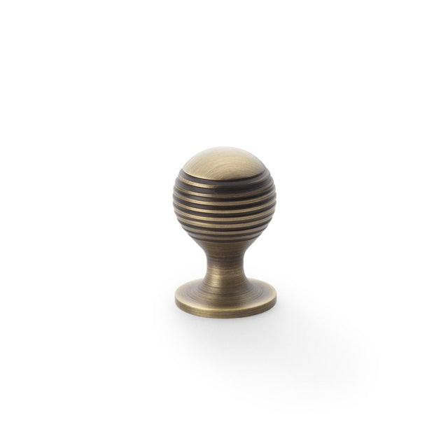 This is an image showing Alexander & Wilks Caesar Cupboard Knob on Round Rose - Antique Brass - 25mm aw832-25-ab available to order from Trade Door Handles in Kendal, quick delivery and discounted prices.