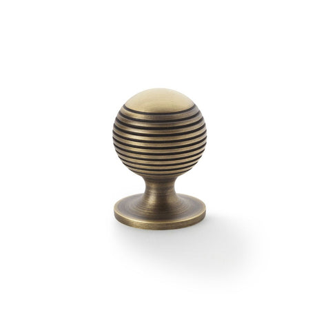 This is an image showing Alexander & Wilks Caesar Cupboard Knob on Round Rose - Antique Brass - 32mm aw832-32-ab available to order from Trade Door Handles in Kendal, quick delivery and discounted prices.